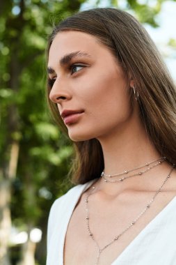 Güzel genç bir kadın zarif bir şekilde durur, göz kamaştırıcı mücevherlerle süslenir, güzelliğe daldırılır..