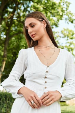 Canlı yeşil bir parkta, genç ve güzel bir kadın beyaz bir elbise içinde kendine güven yayıyor..