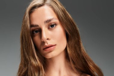 Genç ve güzel bir kadın düşünceli bir şekilde doğal güzelliğini ve çekiciliğini kapalı alanda sergiliyor..