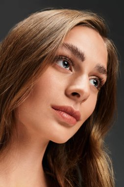 Genç ve güzel bir kadın düşünceli bir şekilde, çarpıcı özelliklerini ve yumuşak ifadesini sergiliyor..