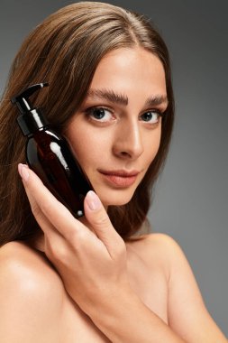 Genç bir kadın elinde bir deri şişesi tutarken gülümsüyor, güzel ve kendine güvenen..