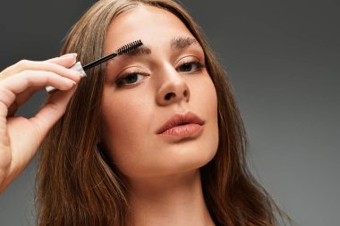 Genç bir kadın şık bir ortamda kaşlarını tımar ederken dikkatle odaklanır..