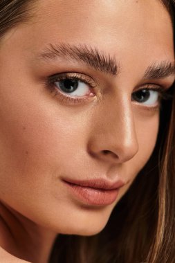 Genç ve güzel bir kadın kendinden emin bir şekilde, etkileyici gözleri ve çarpıcı cilt tonlarıyla bakar..