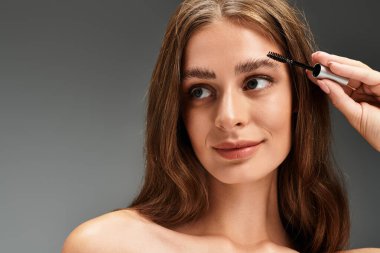 Güzel bir genç kadın kaş jölesi sürüyor. Güzelliğini ve özgüvenini gösteriyor..