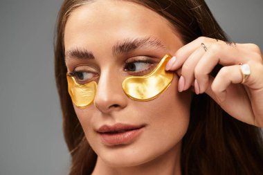 Güzel genç bir kadın altın göz bantları takar, bir anlık özgüven ve rahatlama ile.