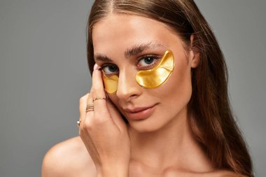 Genç bir kadın, güzelliğini arttırmak için altın maskeler takıp kameraya gülümsüyor..