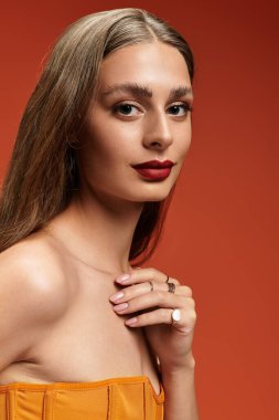 Genç bir kadın zarifçe poz verir, parlak cildiyle ve şık, ılık makyajıyla hava atar..