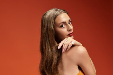 Genç ve güzel bir kadın zarif bir şekilde poz veriyor, şık kıyafetlerini ve çarpıcı özelliklerini vurguluyor..