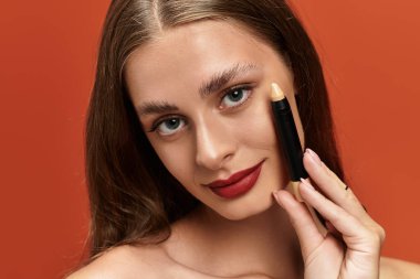 Uzun saçlı genç kadın makyaj yapıyor, sanatsal yeteneğini ve özgüvenini vurguluyor..