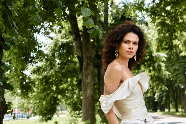 A young woman in a white dress stands gracefully among vibrant greenery.