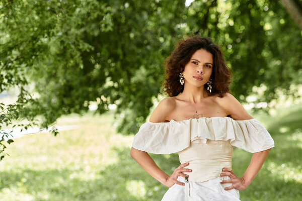 Young woman in a white summer dress exudes confidence surrounded by lush greenery.