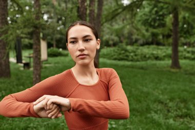 Genç, güzel yoga eğitmeni yemyeşil bir ortamda farkındalık ve denge pratiği yapıyor..
