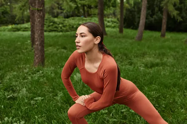 Genç bir yoga öğretmeni, doğayla bağlantı kuran canlı yeşil bir ortamda farkındalık uygular..
