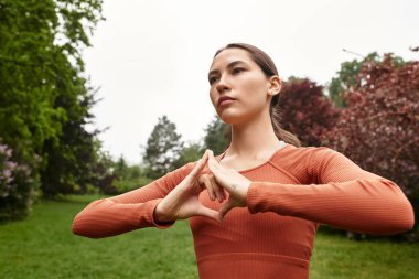 Genç, güzel yoga öğretmeni huzurlu bir park ortamında zarif bir duruş sergiliyor..