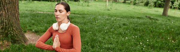 Serene woman engages in yoga practice, fostering inner peace among lush grass and trees.