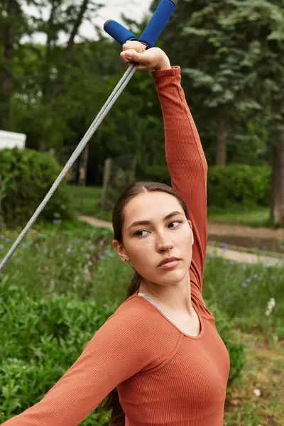 Genç bir kadın yoga pozları verirken yemyeşil bir bahçede sakinliğin tadını çıkarıyor..