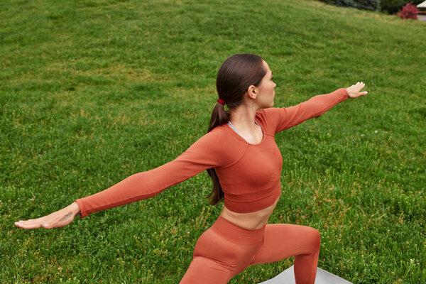 Elegantly poised in warrior pose, the young yoga teacher inspires tranquility in the lush park.