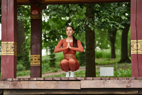 A young woman practices yoga in nature, showcasing strength and balance in a serene environment.