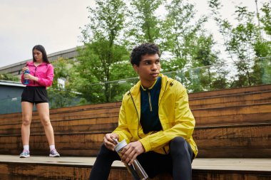 İki sportif birey, spor yaptıktan sonra temiz havanın ve dinlenmenin tadını çıkarıyor..