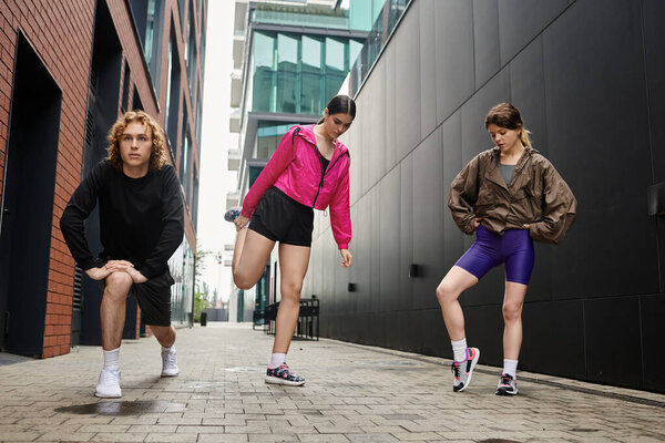 Young athletes prepare to run by stretching together in a lively city environment.