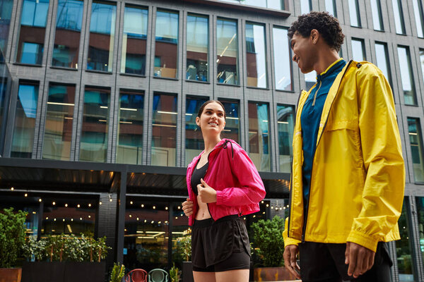 Два спортсмена разговаривают и улыбаются в спортивной одежде под ясным небом.