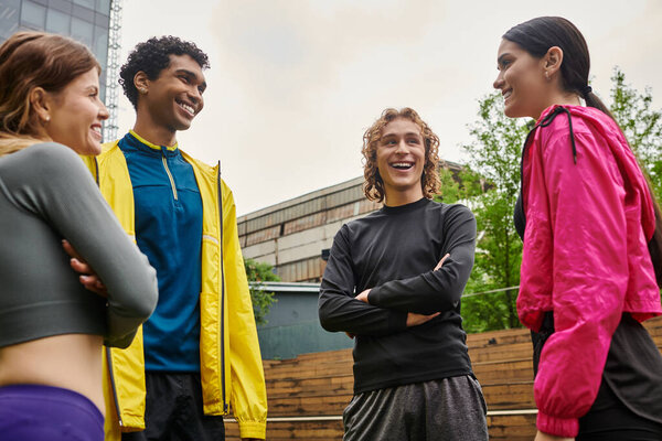 Four young, sporty individuals connect and share laughter while training together outdoors.