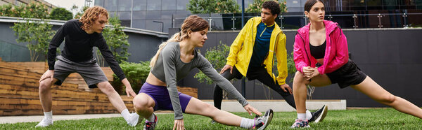 Днем четыре юных спортсмена занимаются разминкой на пышной зеленой лужайке в городе.