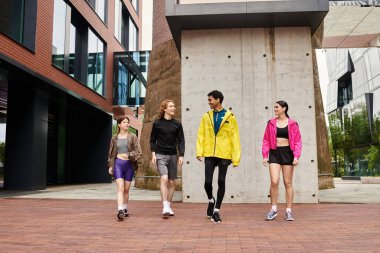 Dört sportif birey enerjiyle dolu modern bir şehirde canlı bir yürüyüş yapıyorlar..