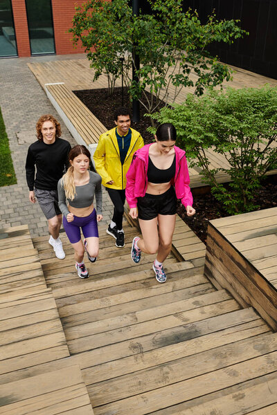 Четыре энергичных молодых человека бегут по деревянным ступенькам в солнечный день на свежем воздухе.