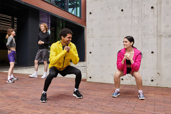 Energetic group of young people performing squats in a modern urban park during daylight hours.