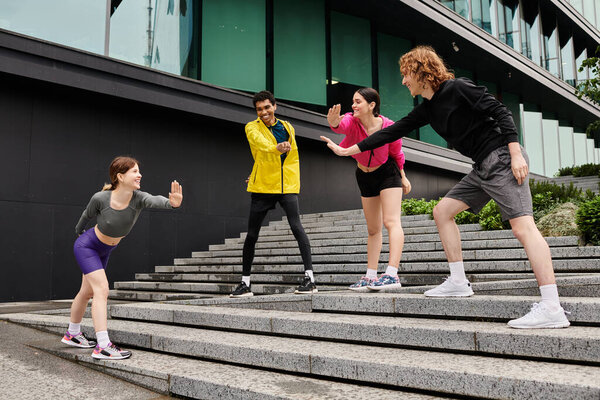 Group of young, sporty individuals displaying playful athleticism on outdoor stairs during daytime.