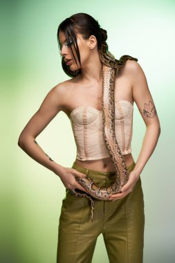 Genç bir kadın yılanla poz verir, güzellik ve tehlikenin bir karışımıdır..