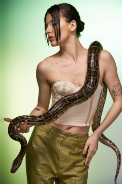 Genç bir kadın, büyük bir yılanı tutarken güzellik ve cesaretle büyülenir..