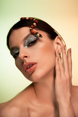 Çekici genç bir kadın bir yılanla şakalaşırken güzelliğini sergiliyor..