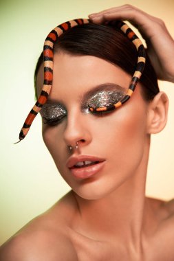 Genç bir kadın, zarif bir şekilde başının etrafında kıvrılarak büyüleyici makyajını sergiliyor..