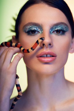 Genç bir kadın sanatsal bir ortamda çarpıcı bir yılanla cesur bir poz verir..