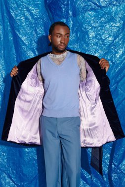 Şık giyinmiş yakışıklı genç adam hazır duruyor, canlı bir şekilde kıyafetlerini sergiliyor..