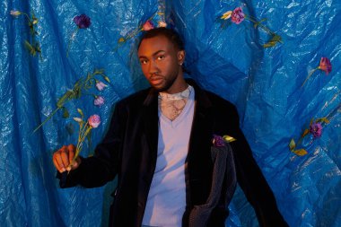 Şık bir genç adam kendine güveni canlı çiçeklerin yanında, zarafet ve cazibesini sergiliyor..