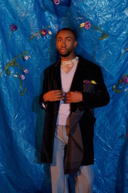 Yakışıklı genç bir adam şık kıyafetini güzel mavi bir arka planda sergiliyor..