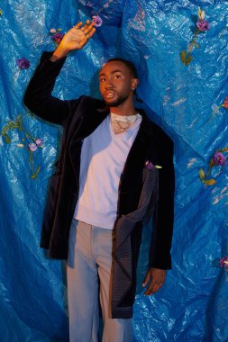 Genç bir adam canlı mavi bir arka plana karizma ve tarz yayar..