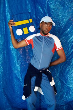 Şık bir genç adam spor kıyafetleri içinde kendine güvenen renkli bir teyple poz veriyor..