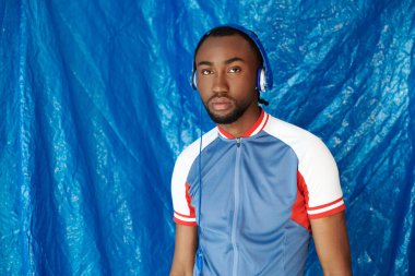 Şık giyinmiş, kulaklıklı, kendine güvenini gösteren karizmatik bir genç adam..