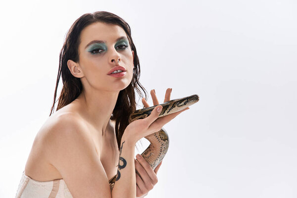 Молодая красивая женщина демонстрирует свою силу и привлекательность, позируя со змеей..