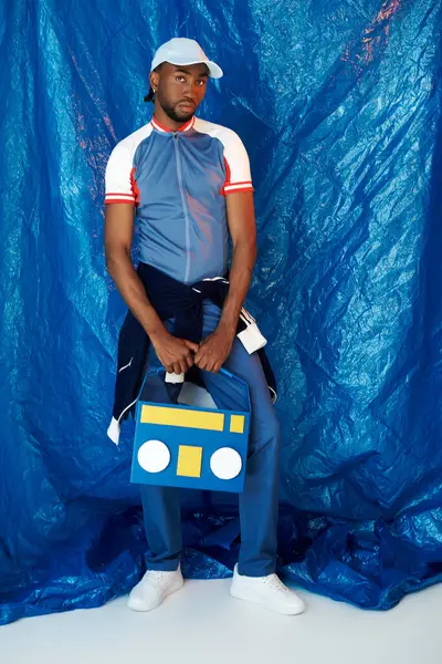 Yakışıklı bir genç adam havalı bir tavırla duruyor, canlı mavi bir modern moda sergiliyor..