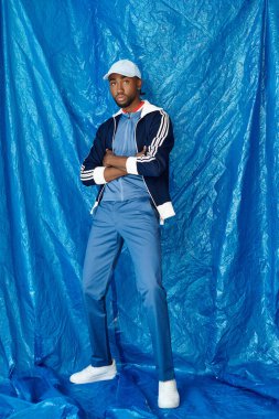 Genç bir adam kendine güveni ve cazibesini parlak mavi bir arka plana yayar..