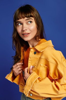 Genç bir kadın, parlak bir ortamda ceketini hazırlarken moda anlayışını sergiliyor..