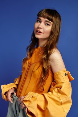 Genç bir kadın, eşsiz kıyafetini canlı mavi bir arkaplanda sergiliyor..