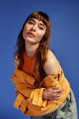 Moda anlayışını gösterirken şık giyinmiş çekici genç bir kadın şakacı pozlar veriyor..