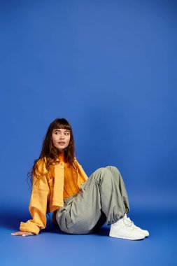 Şık giyinmiş genç bir kadın zarif bir şekilde oturur, kendine güven ve tarz yayar..