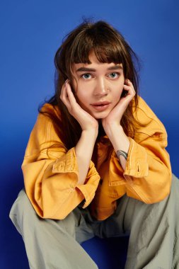 Genç bir kadın, otururken, kişiliğini yansıtırken eşsiz tarzını sergiliyor..